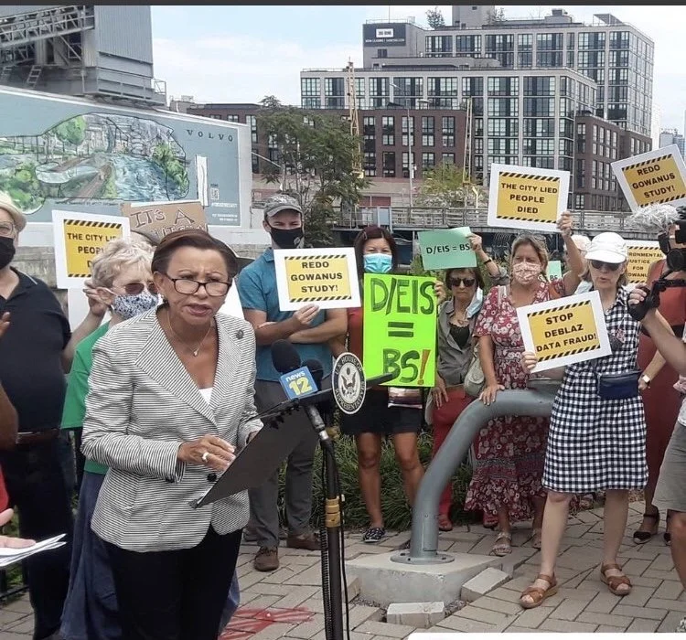 Public official and protesters holding anti-rezoning and environmental review signs.